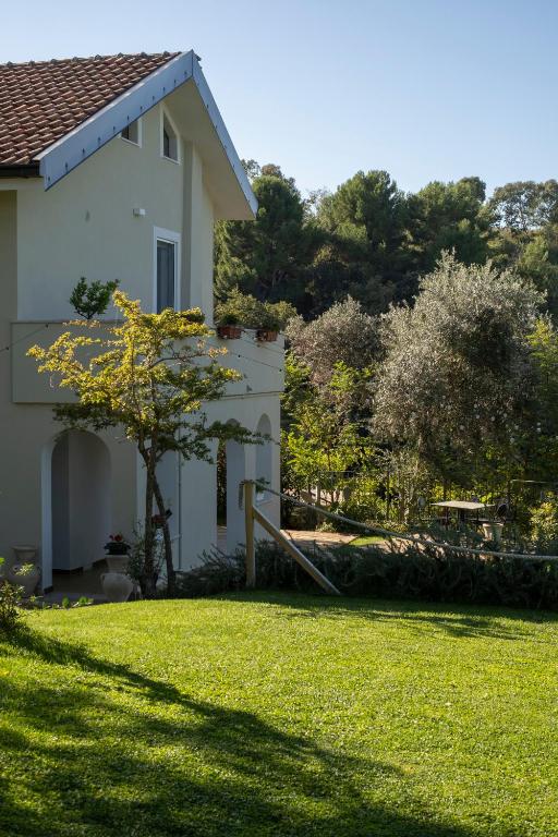 a white house with a grass yard and a tree at Rosmaris - Villa nel verde in Francavilla al Mare
