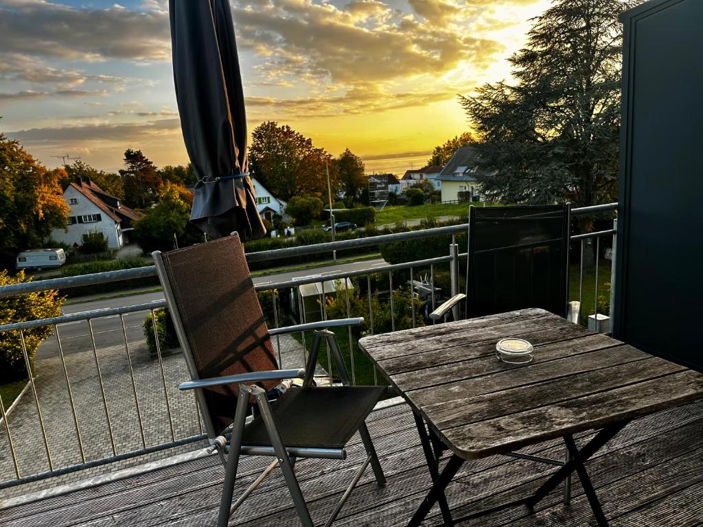 a wooden table and chair on a deck with an umbrella at Deluxe Apartment Seeblick in Friedrichshafen