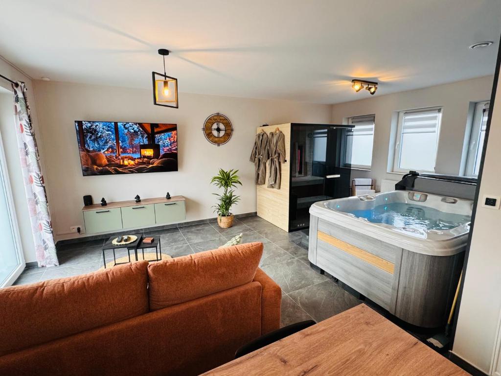 ein Wohnzimmer mit einem Sofa und einer Badewanne in der Unterkunft Le cocon de pernelle spa et sauna privatif in Couvin