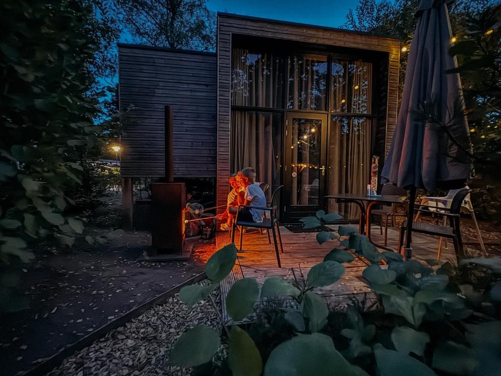a woman sitting in a chair on a patio at night at Holiday Home Maridu Tiny Cube in Arnhem