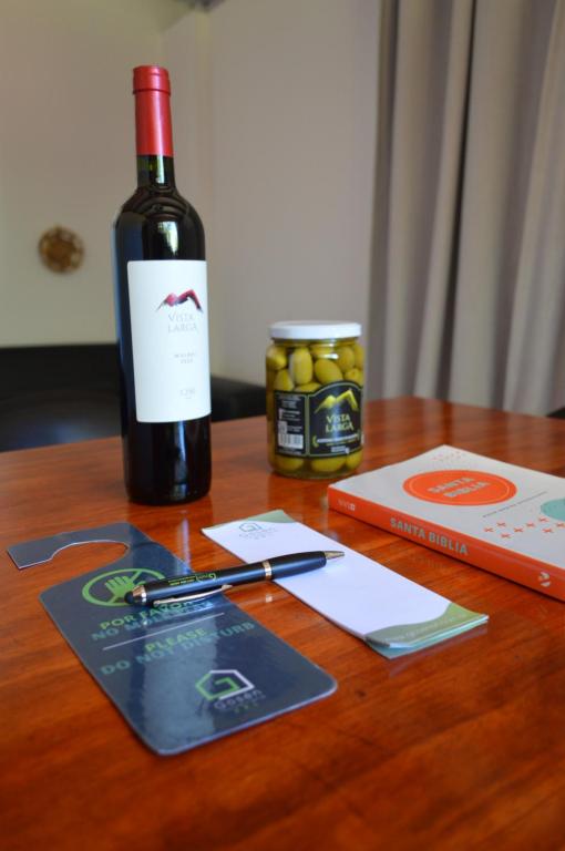 a bottle of wine sitting on a wooden table with a pen at Gosén Cabañas Sanagasta in Villa Bustos