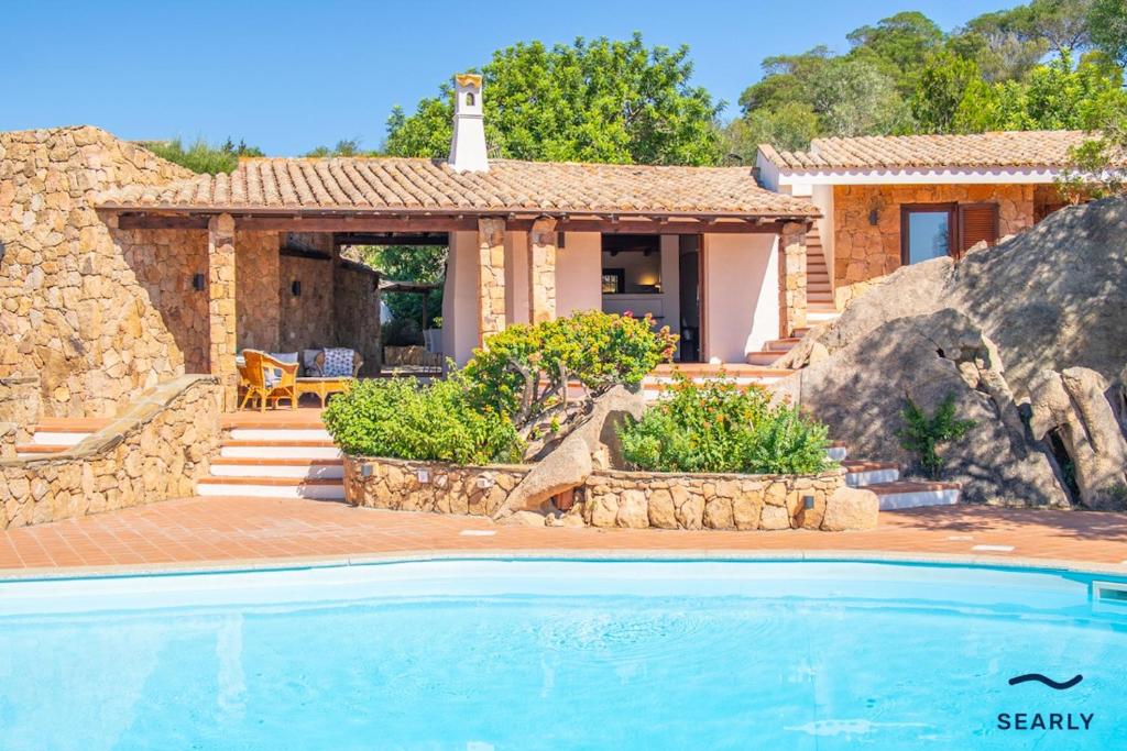 a house with a swimming pool in front of a house at Villa San Teodoro - By Searly in Punta Molara