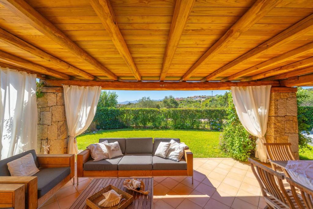 a wooden pergola with a couch on a patio at Villa Molara Home - By Searly in Punta Molara