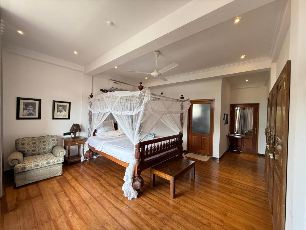 a bedroom with a canopy bed and a couch at Margaret House in Mirissa