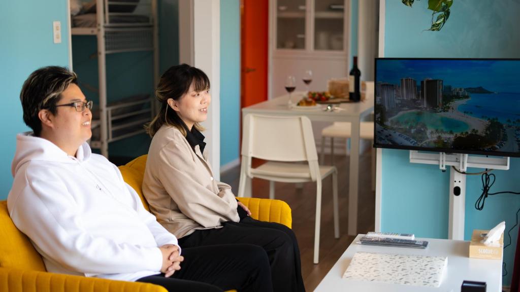 a man and woman sitting in chairs in front of a computer at 佐世保まち宿 in Sasebo