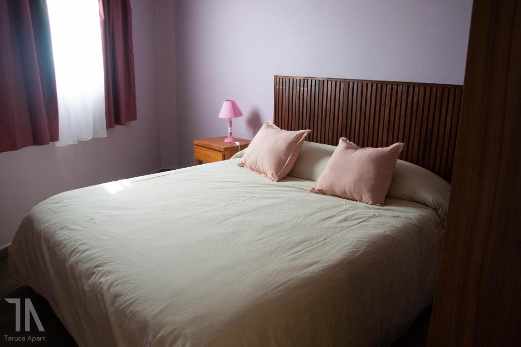 una camera da letto con un grande letto con cuscini rosa di Taruca Apart a Ciudad Evita