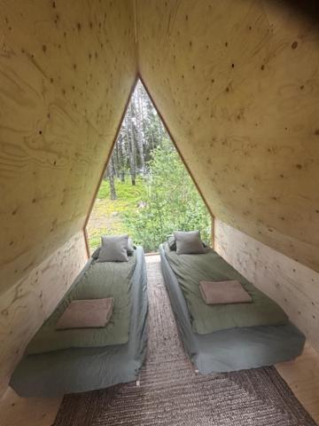 two beds in a room with a large window at Forest View Cottage 