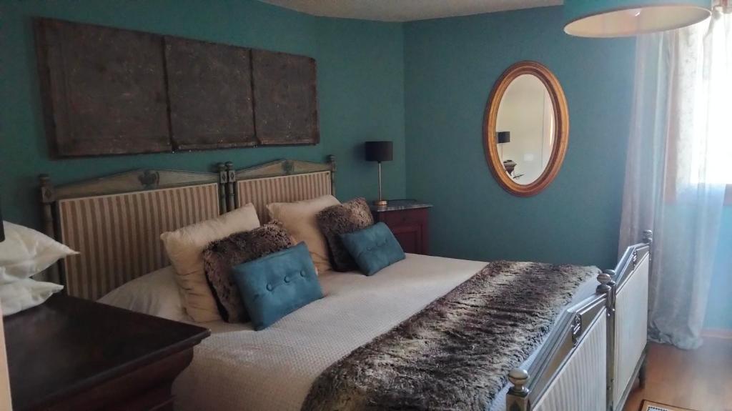 een slaapkamer met een groot bed met een spiegel bij Maison Jacquemin in Saint-Pierre