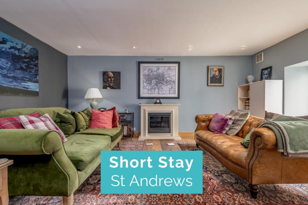 a living room with two green couches and a fireplace at Kincaple Garden Flat - Kincaple in Guard Bridge