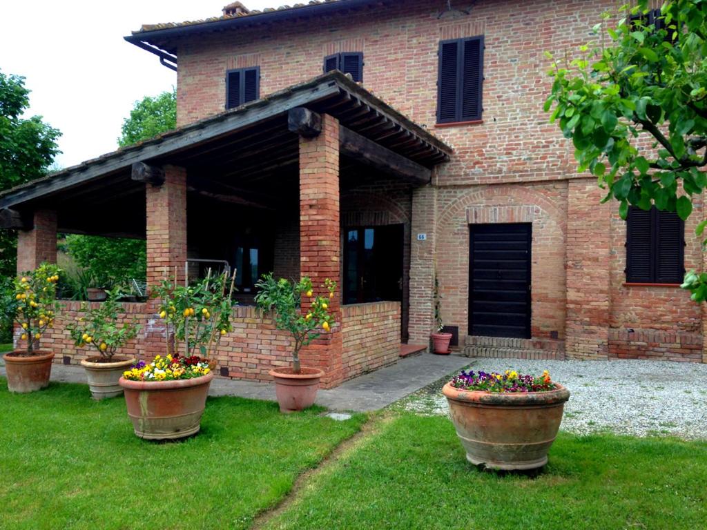 シエナにあるLovely Tuscan Country Houseの煉瓦造りの家の前の鉢植えの群れ
