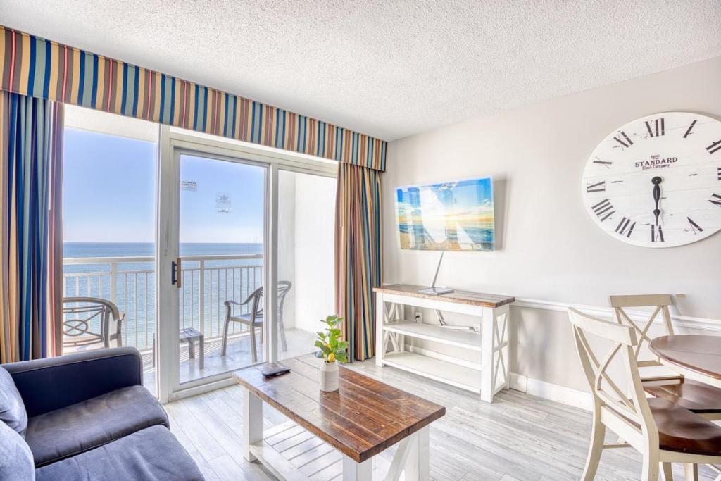 マートルビーチにあるCamelot by the Sea Resort Unit 1205 Direct Oceanfront Condo with Balconyのリビングルーム(壁掛け時計、テーブル付)