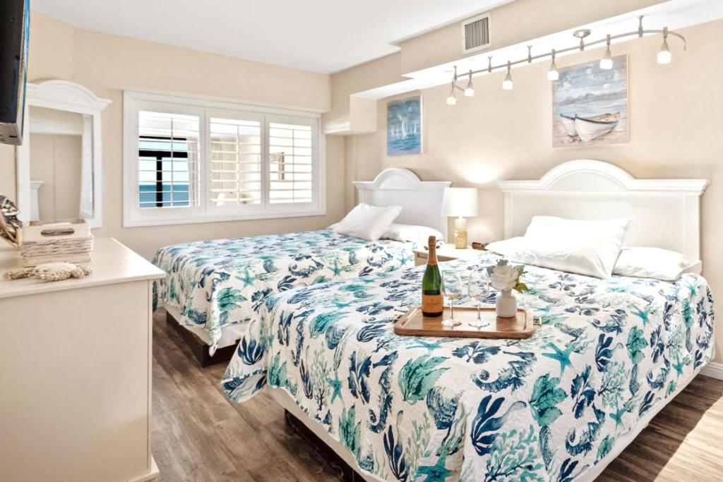 een slaapkamer met twee bedden en een tafel met een fles champagne bij Beach Cove Resort Unit 423 Oceanfront Condo with Balcony in Myrtle Beach