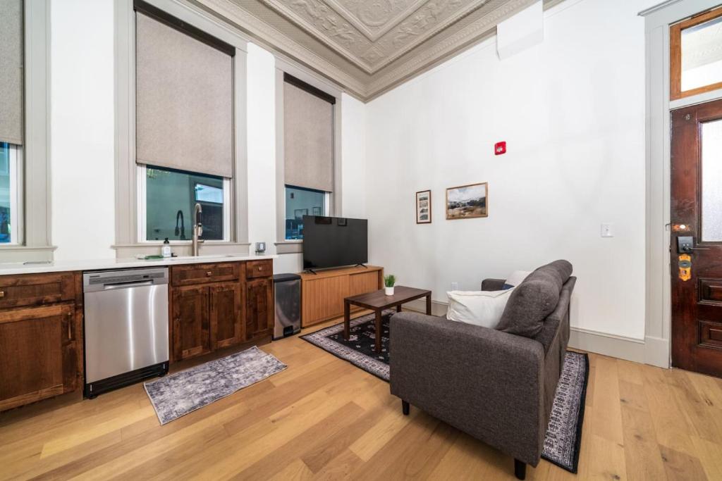 een woonkamer met een bank en een keuken met een tv bij Candlestick Suite in Sedalia