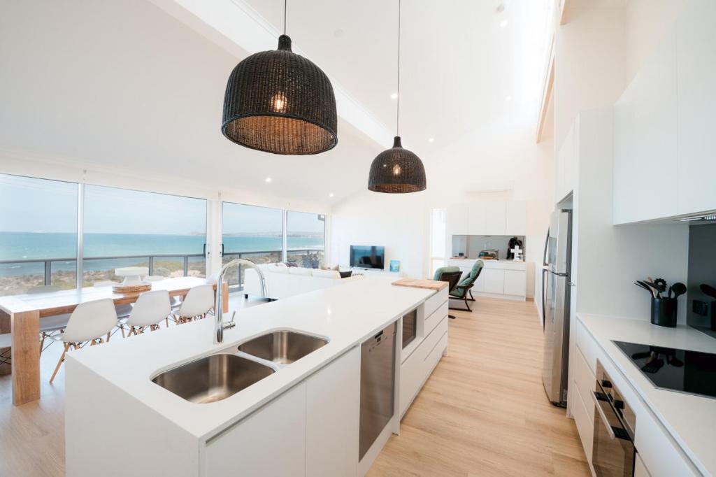 a kitchen and dining room with a view of the ocean at Oceana - A Panoramic Beachfront Escape for Groups in Port Elliot