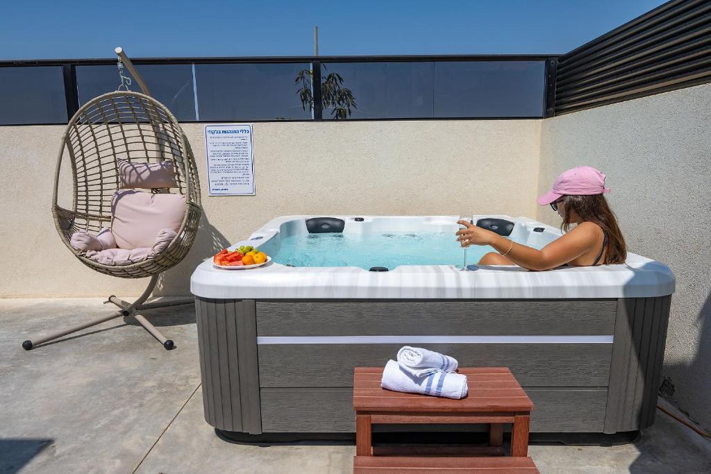 kobieta siedząca w jacuzzi w obiekcie רוי סוויטות בוטיק - 2 סוויטות עם מרפסת פרטית w mieście Jawne’el