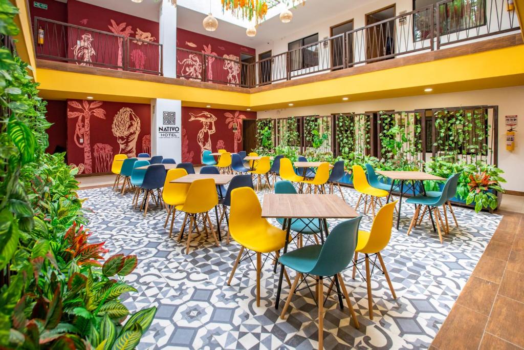 a cafeteria with tables and chairs and plants at Nativo Hotel in Popayan