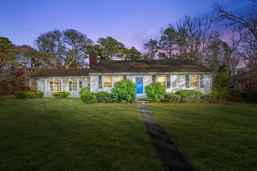 a white house with a blue door on a yard at 350 School House Road Eastham - Beach Dreams in Eastham