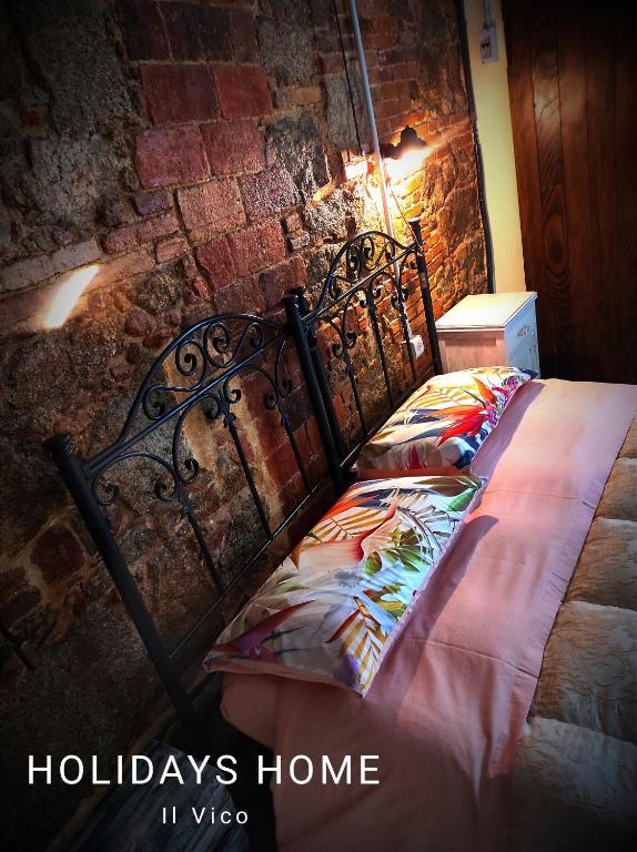 a metal bed in a room with a brick wall at Il Vico holiday home in Serra San Bruno