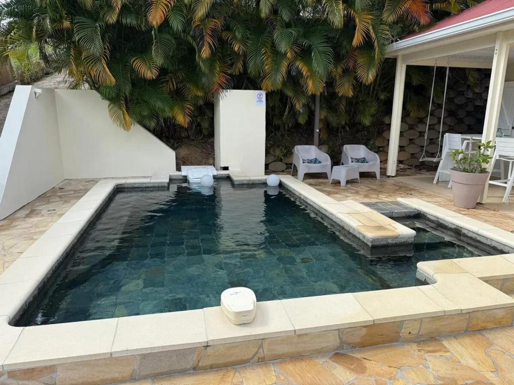 a swimming pool in a backyard with a palm tree at Villa avec piscine privée à Rivière-Salée - 110 m² in Quartier la Fleury Guiné