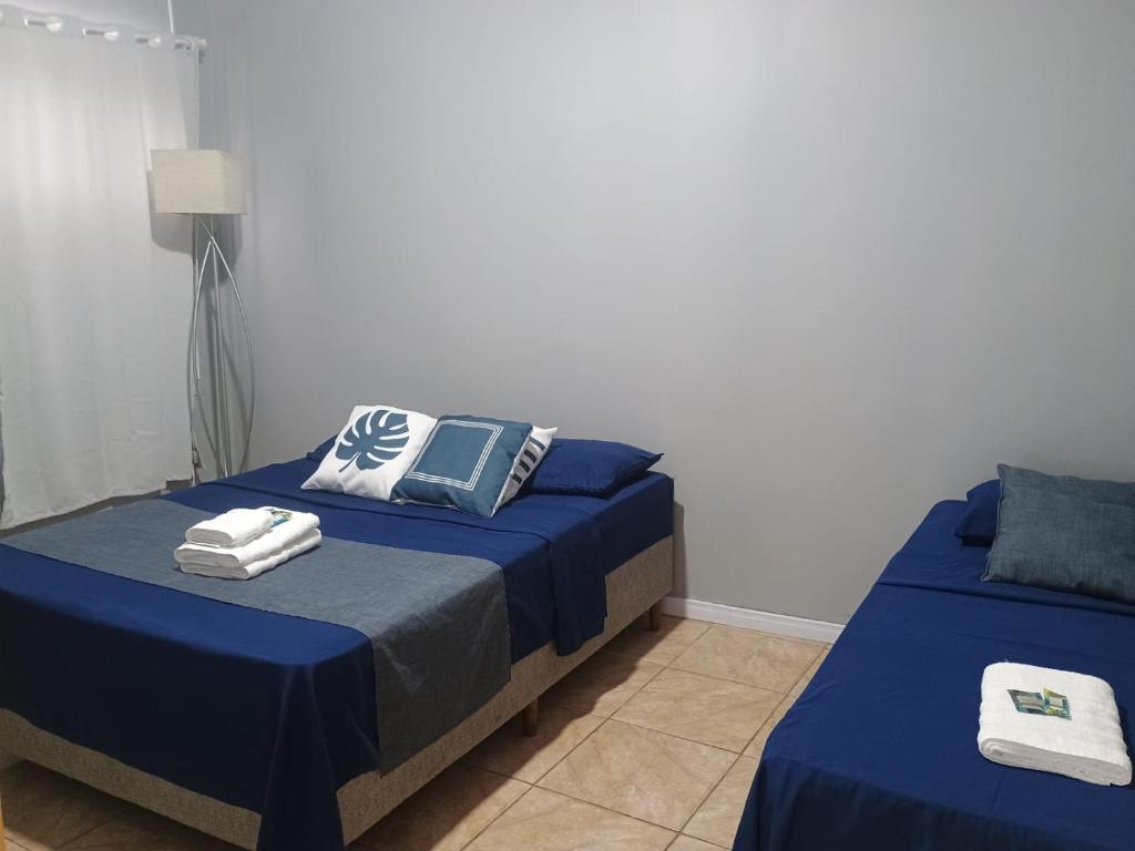 una camera da letto con due letti con lenzuola blu di Apto confortável com Churrasqueira 03 a Cachoeira do Sul