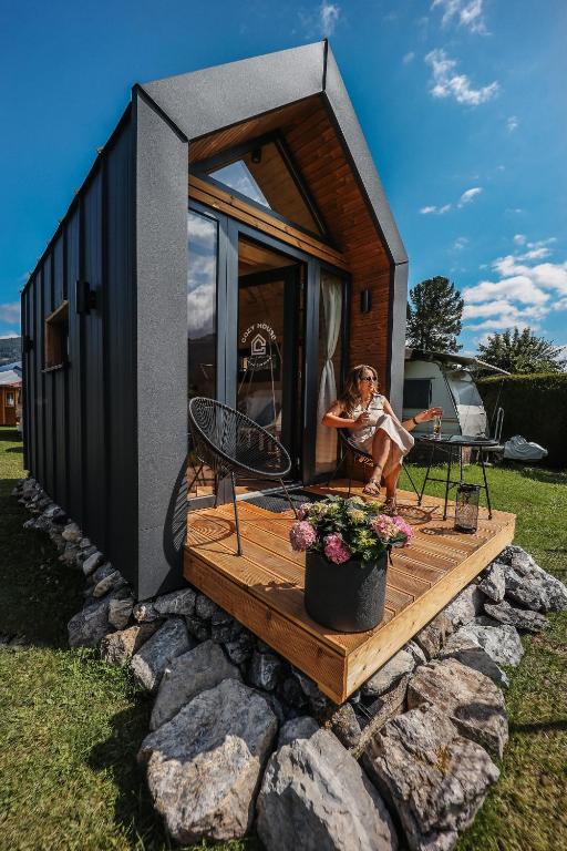 a tiny house with a woman sitting on a deck at Berg & Natur - Cozy house in Altenmarkt im Pongau