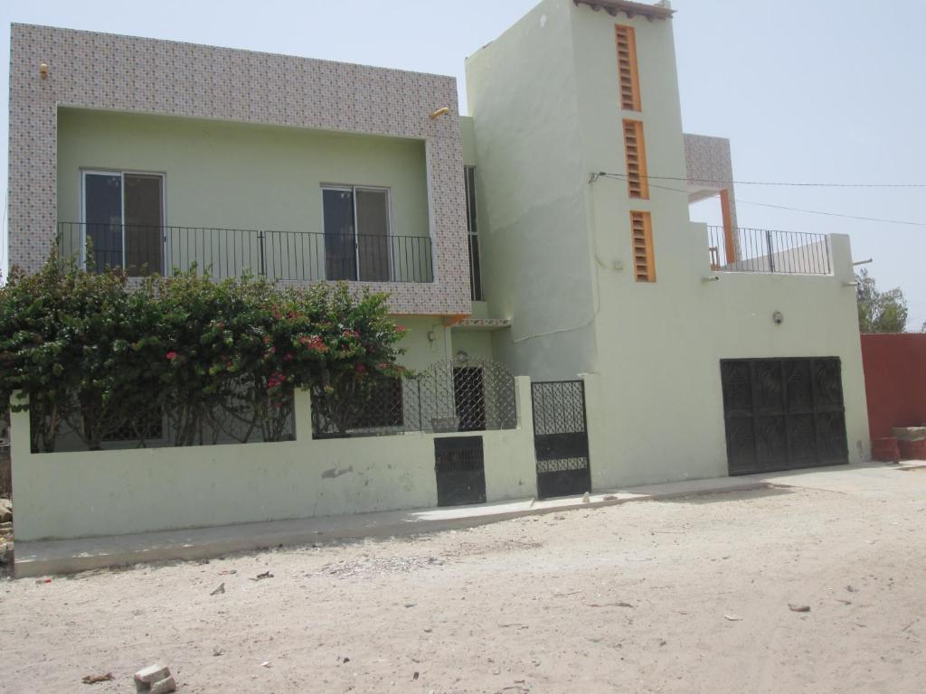 un edificio blanco con una valla y flores. en La Femme Noire, en Joal-Fadiout