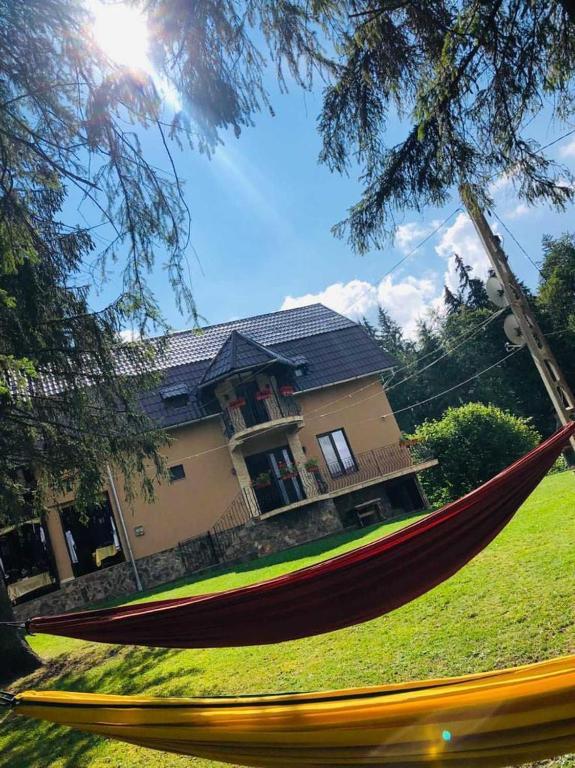 a red hammock in front of a house at Cabana Suvenirurilor in Scărişoara