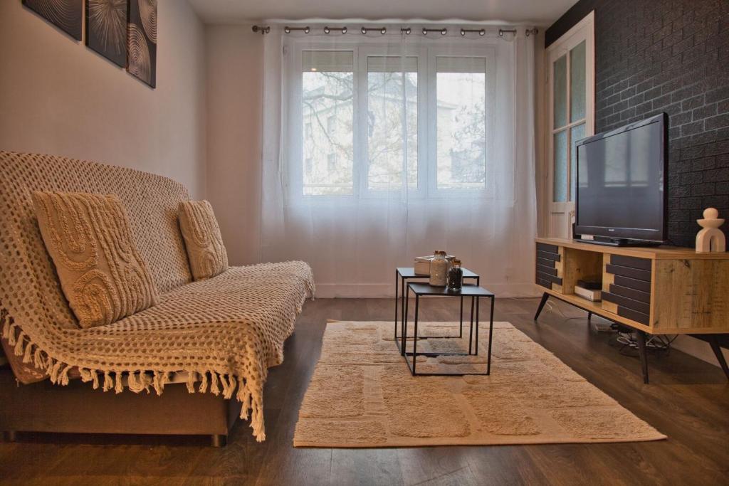 Una sala de estar con un sofá y un televisor. en Escale Atlantique, en Saint-Nazaire