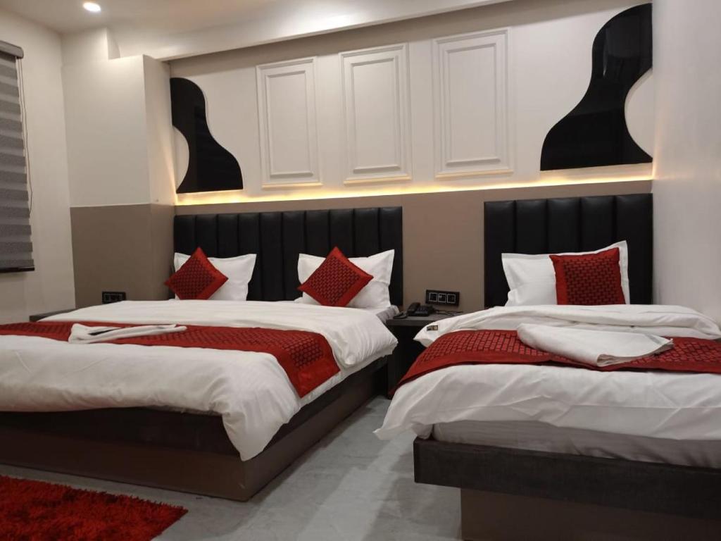 a bedroom with two beds with red and white pillows at Hotel Grand C & G at Central Delhi New Delhi in Jāmb