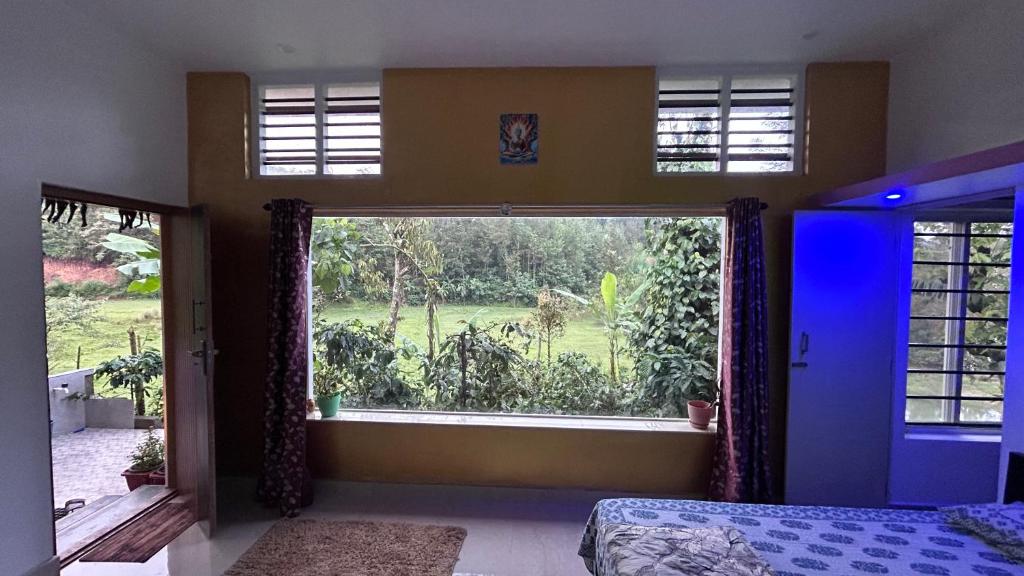 a bedroom with a large window with a view of a yard at Doddakallu Betta Homestay Coorg in Somvārpet