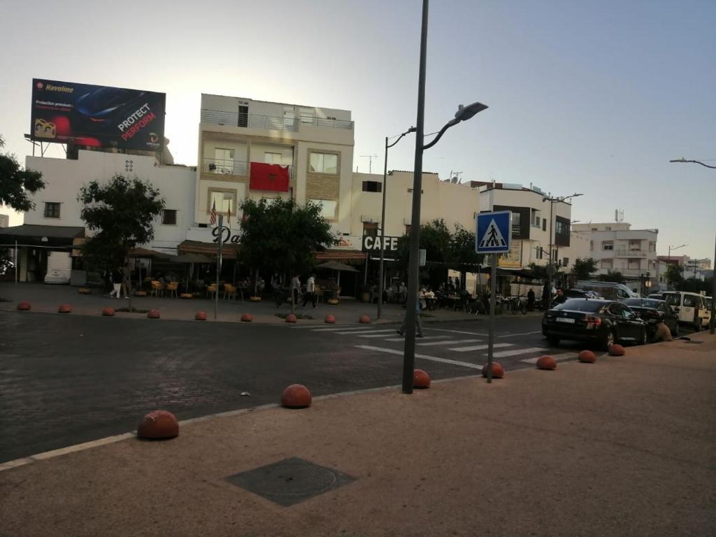 a city street with cars parked in front of buildings at complex mousse in Oulad Akkou