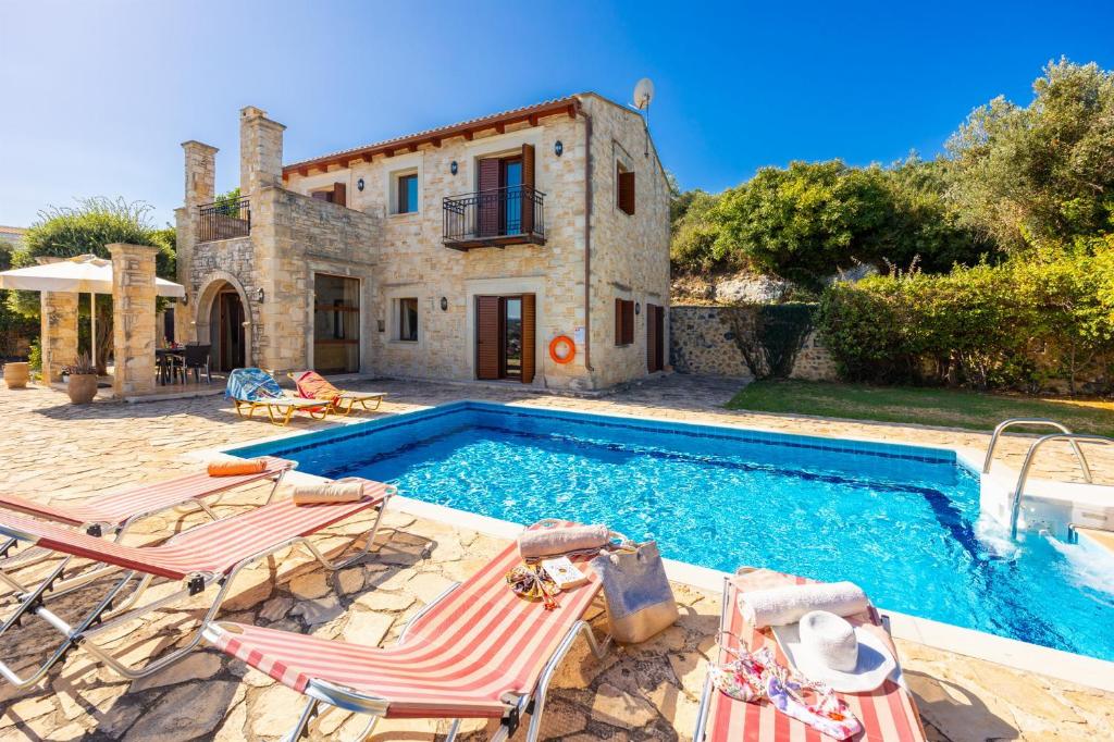 a villa with a swimming pool in front of a house at Teacher Cottage in Agia Triada