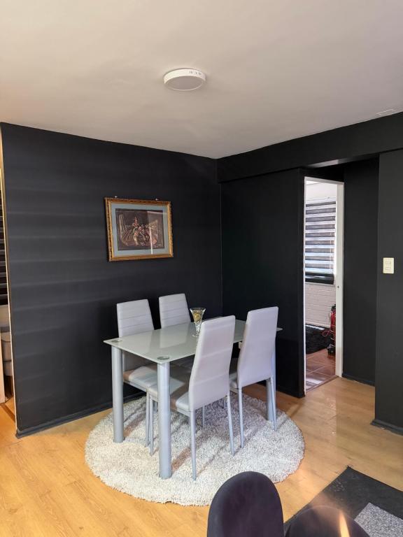 a dining room with a table and white chairs at Departamento cerca de la playa in La Serena