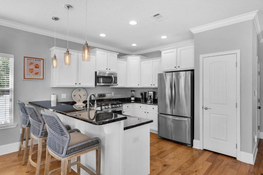 a kitchen with white cabinets and a stainless steel refrigerator at Sunlit Sands in Inlet Beach