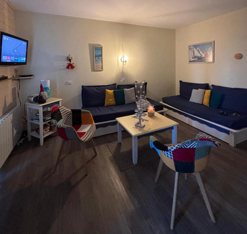 a living room with a blue couch and a table at Les Terrasses des Sables Blancs in Douarnenez