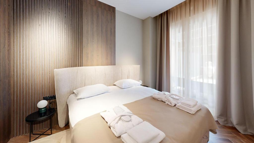 Ideal Apartments في بانيا لوكا: غرفة نوم بها سرير أبيض كبير مع مناشف عليه