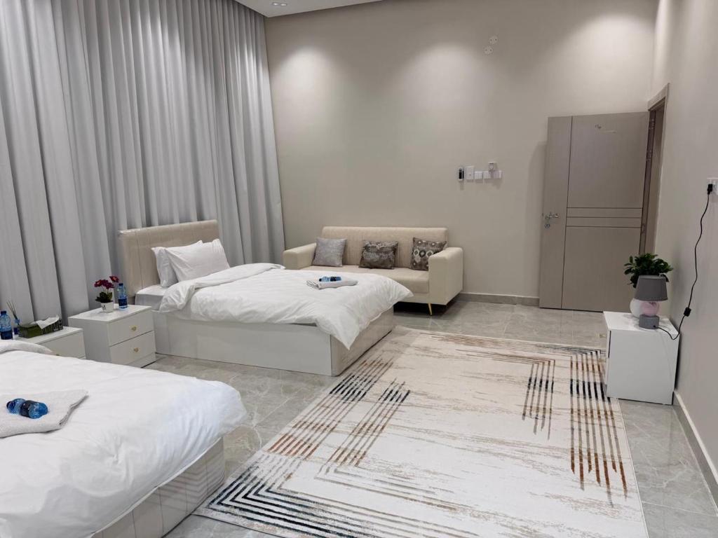 ein Hotelzimmer mit zwei Betten und einer Couch in der Unterkunft فلة الشروق - Sunrise Villa in Sur