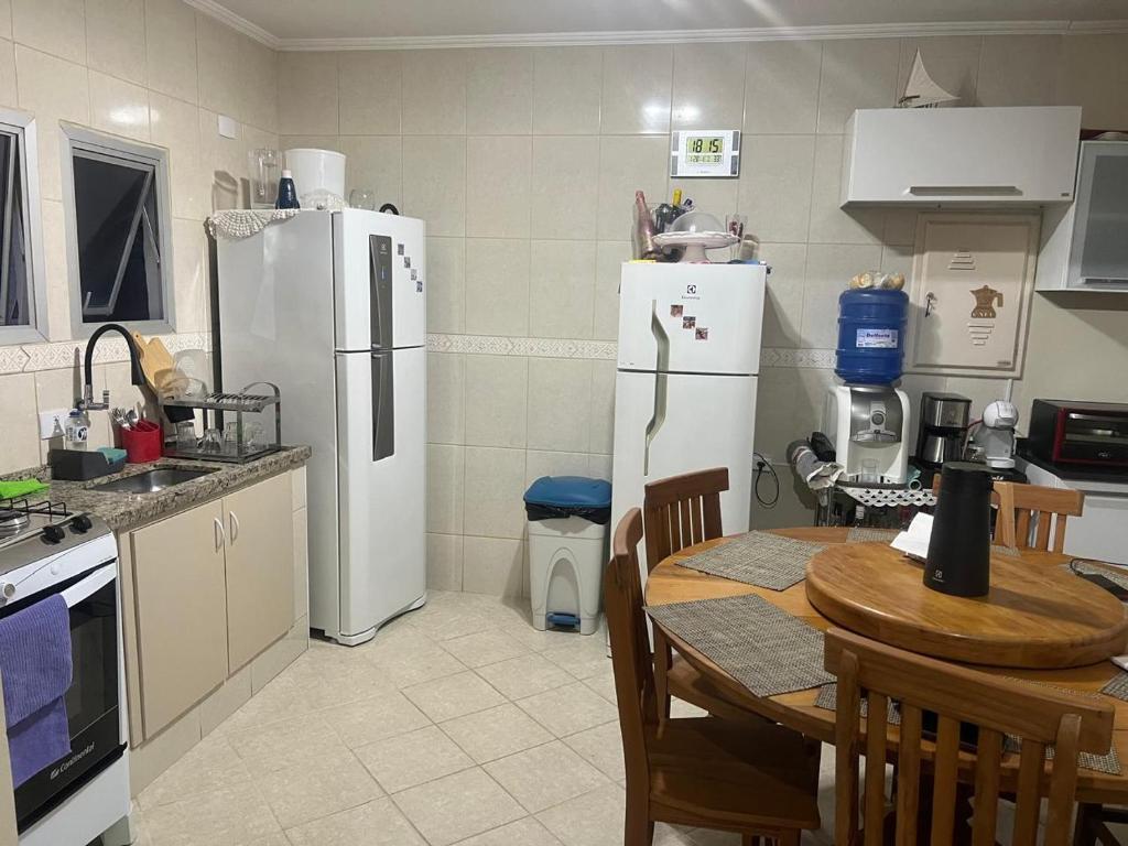 a kitchen with two white refrigerators and a table with chairs at Condomínio Martim de Sá in Caraguatatuba