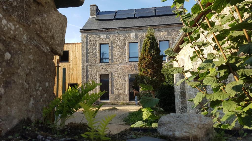 een oud stenen gebouw met een zwart dak bij A la belle étoile - Auberge in Mellionnec