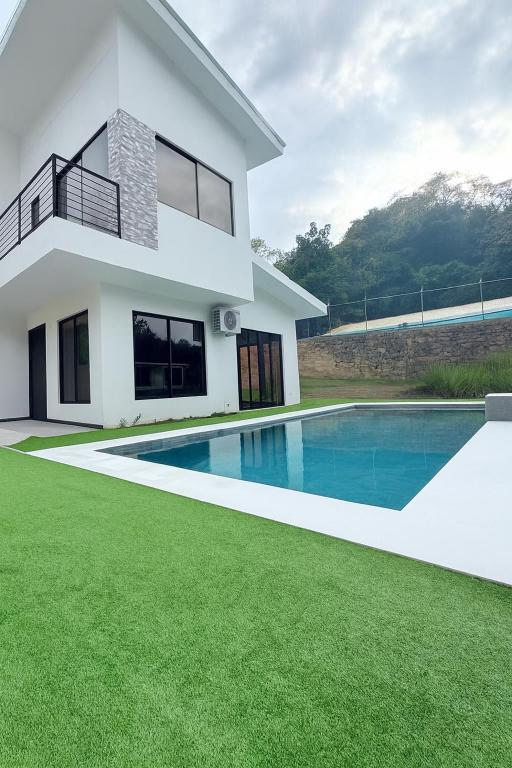 a white house with a swimming pool in front of it at Casa Colibrí Playa Blanca in Paquera