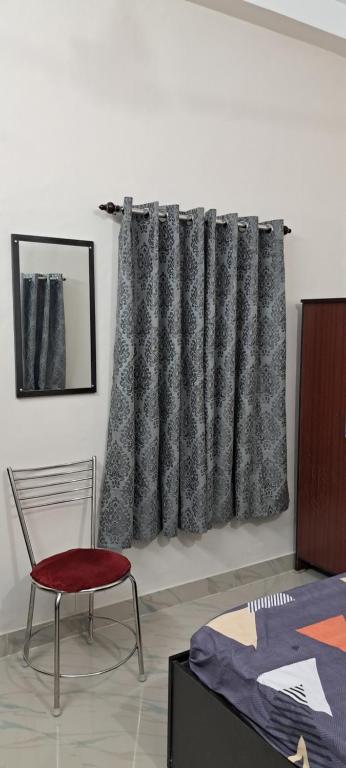 Zimmer mit einem Bett, einem Stuhl und einem Vorhang in der Unterkunft Diya STAYS in Rāmpur Hāt