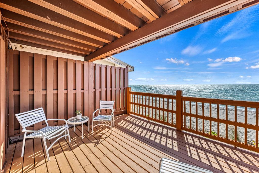 a balcony with two chairs and a table and the ocean at Gulf Front Escape on the Beach with Shared Lounging Deck & Pool in Englewood