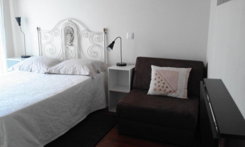 a bedroom with a white bed and a chair at Casa Entre Serras in Donas