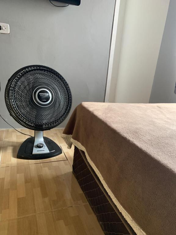 a black fan sitting on the floor next to a table at Casa em Coroados - 800 metros da praia in Guaratuba