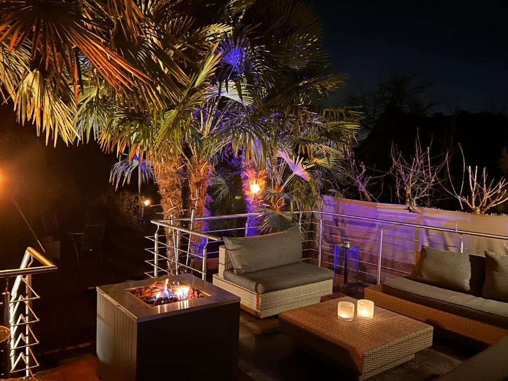 a patio with a couch and a palm tree at night at Sonnendeck - Wellness Whirlpool Garden & Grill,125qm in Meerbusch