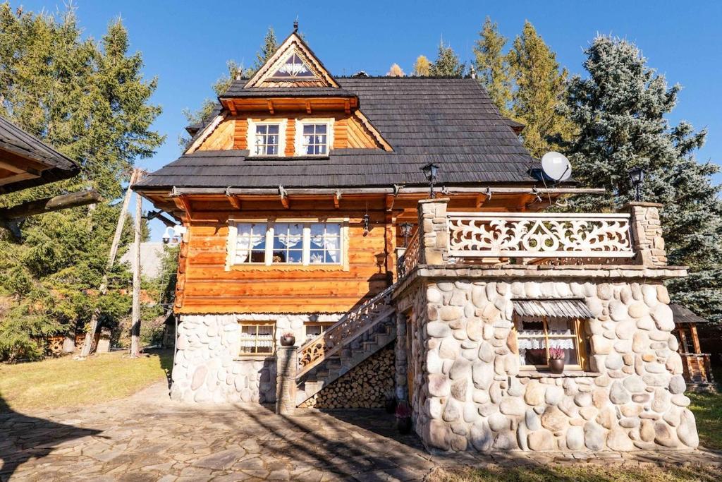 a wooden house with a stone wall at Willa Szept Giewontu-Mountain Base in Kościelisko