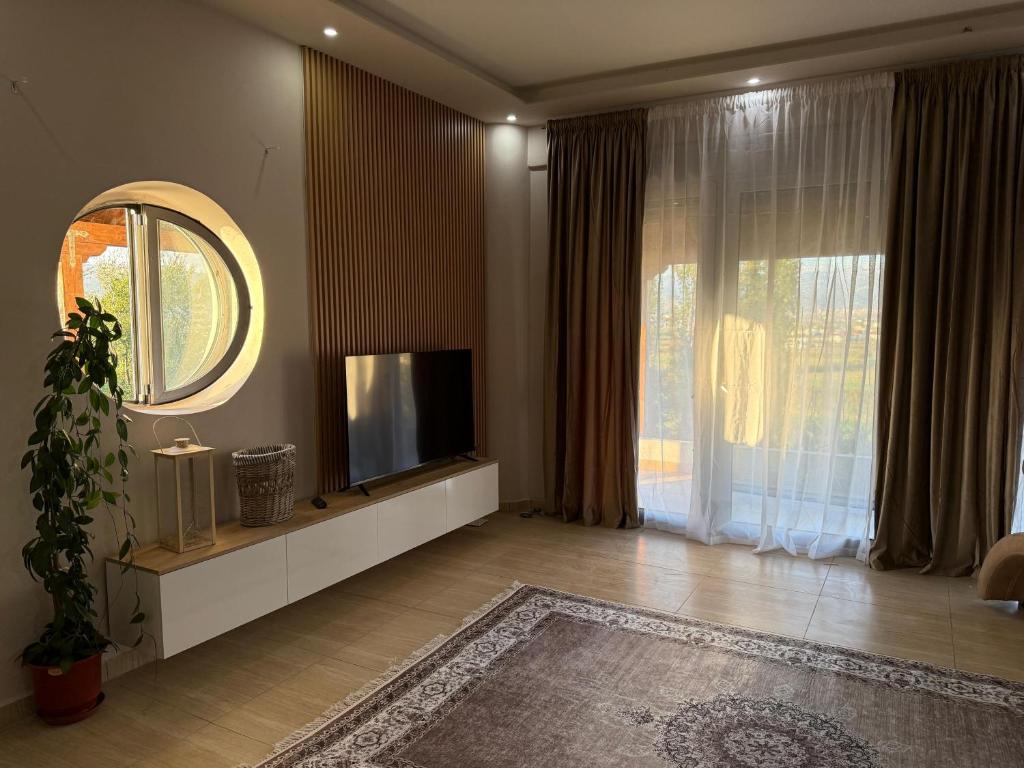 Una sala de estar con televisión y una gran ventana. en Villa Rusi, 