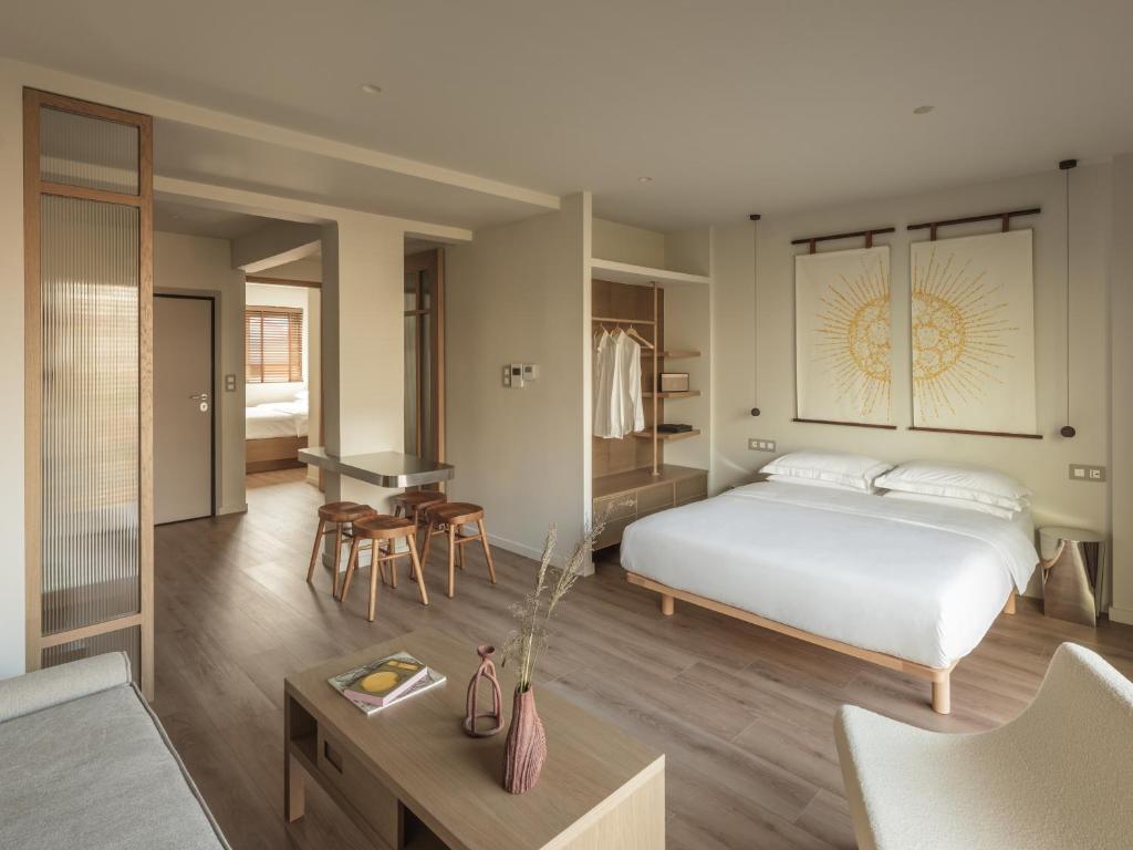 Kaoma Comfort Suites في تريكالا: غرفة نوم مع سرير وغرفة معيشة