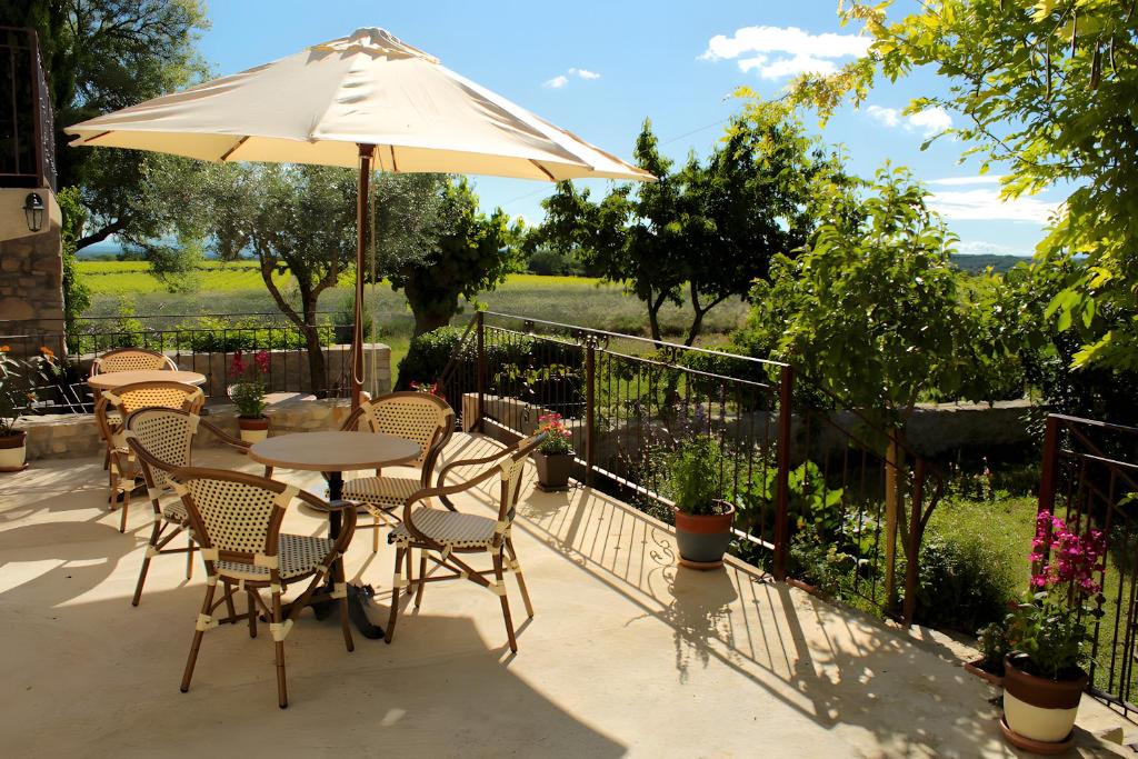 Un patio con una mesa y sillas y una sombrilla. en Gite Domaine De La Bruge, en Saint-Remèze