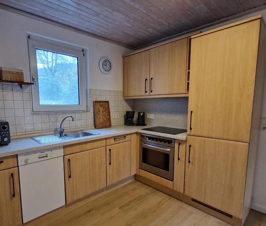 a kitchen with wooden cabinets and a sink and a window at Ferienwohnung Gartenblick in Eslohe